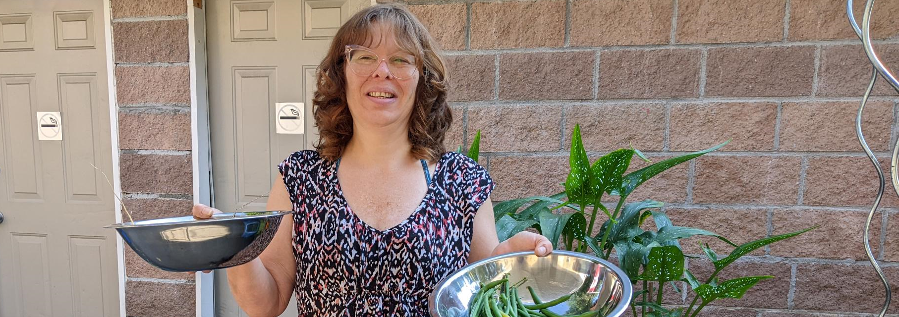 Sally is pictured here holding garden fresh green beans at one of Salus' independent living buildings.